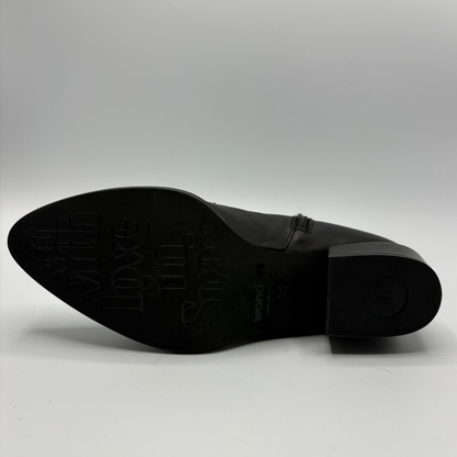 The black sole of a pointed-toe leather shoe photographed against a light gray background.