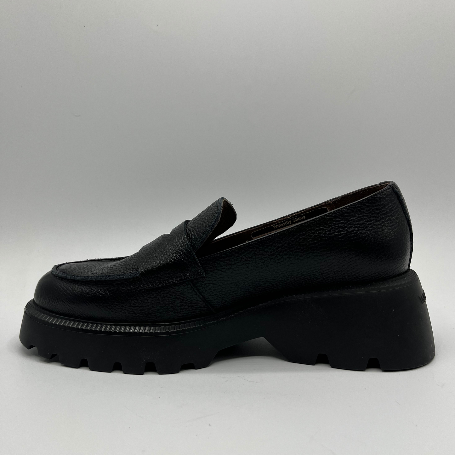 Black loafer shoe on a light gray background