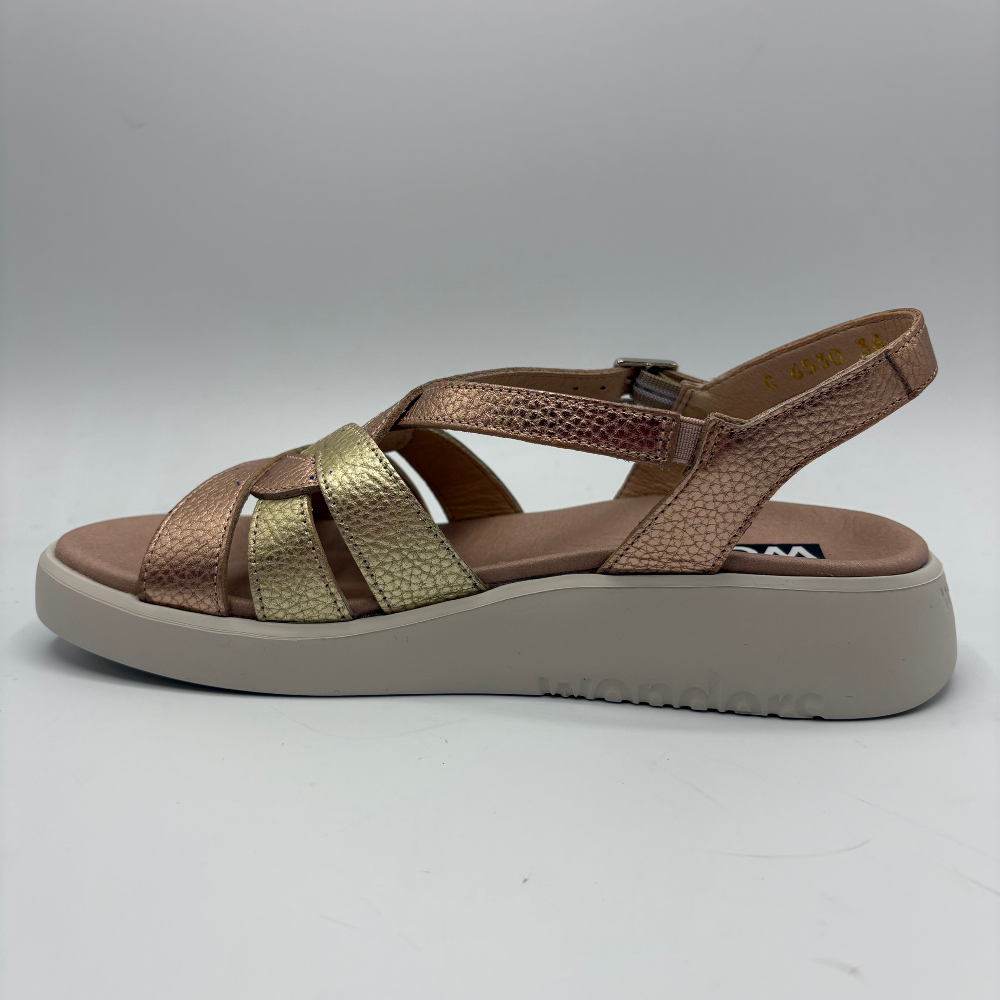 Brown sandal with gold accents on a gray background