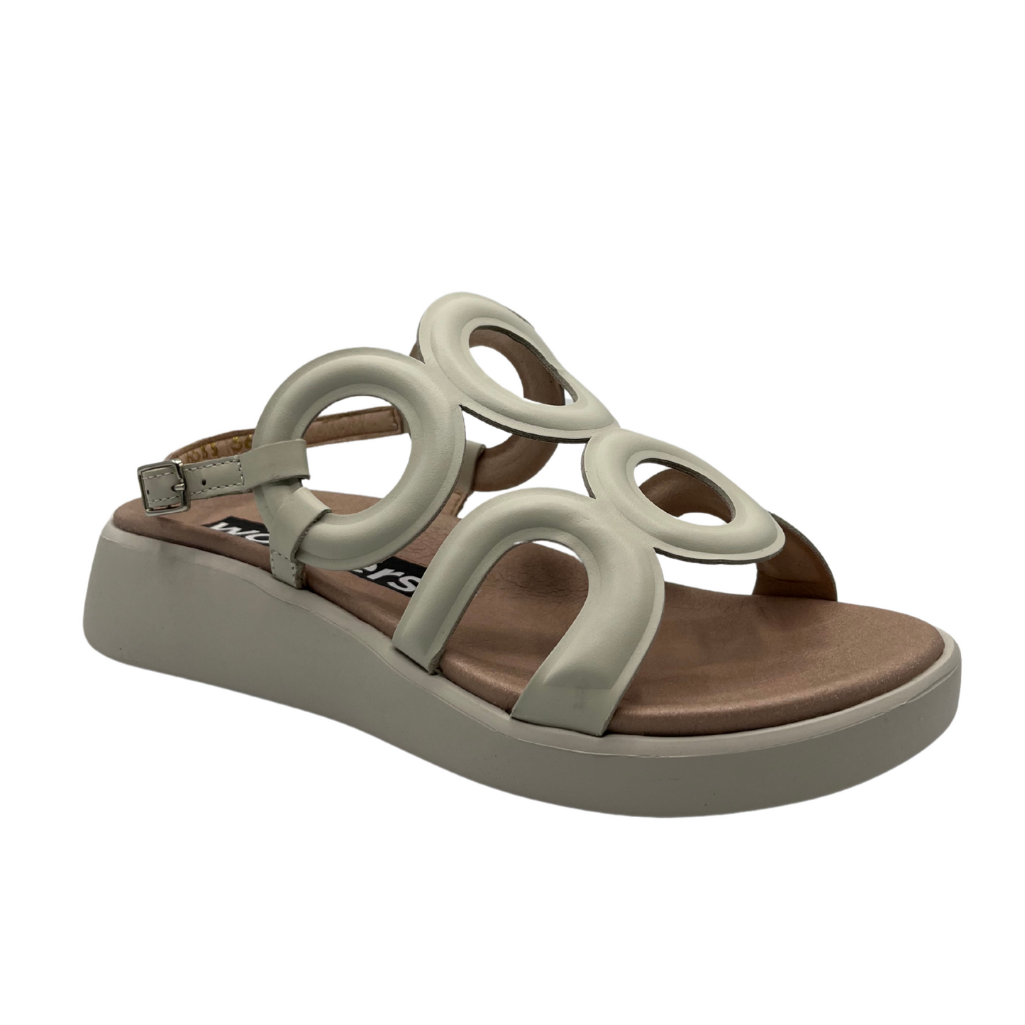 Angled view of cream leather sandal with a circular patterned upper, sling back strap and low wedge outsole.