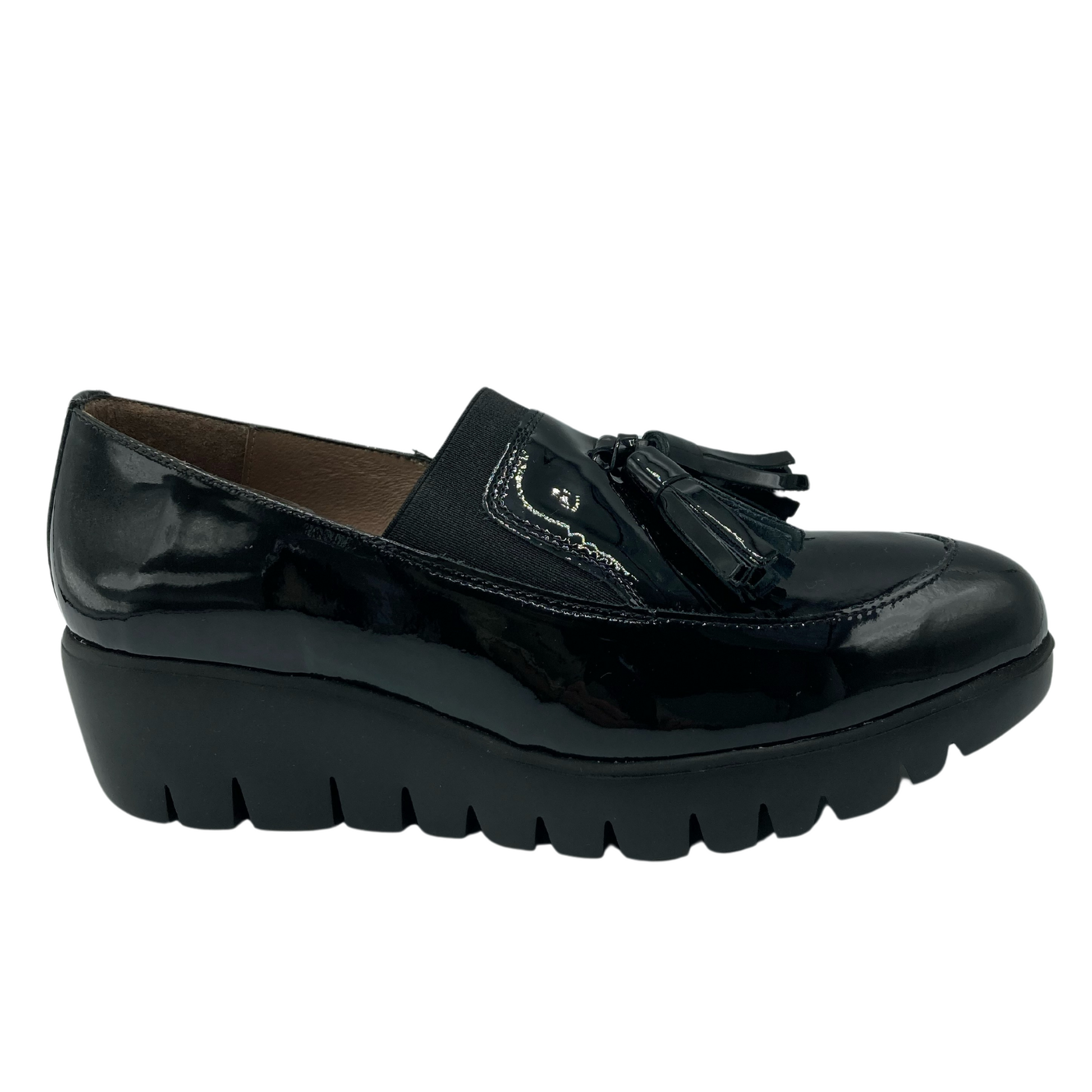 Right facing view of black patent leather wedge loafer with tassels on the toe box