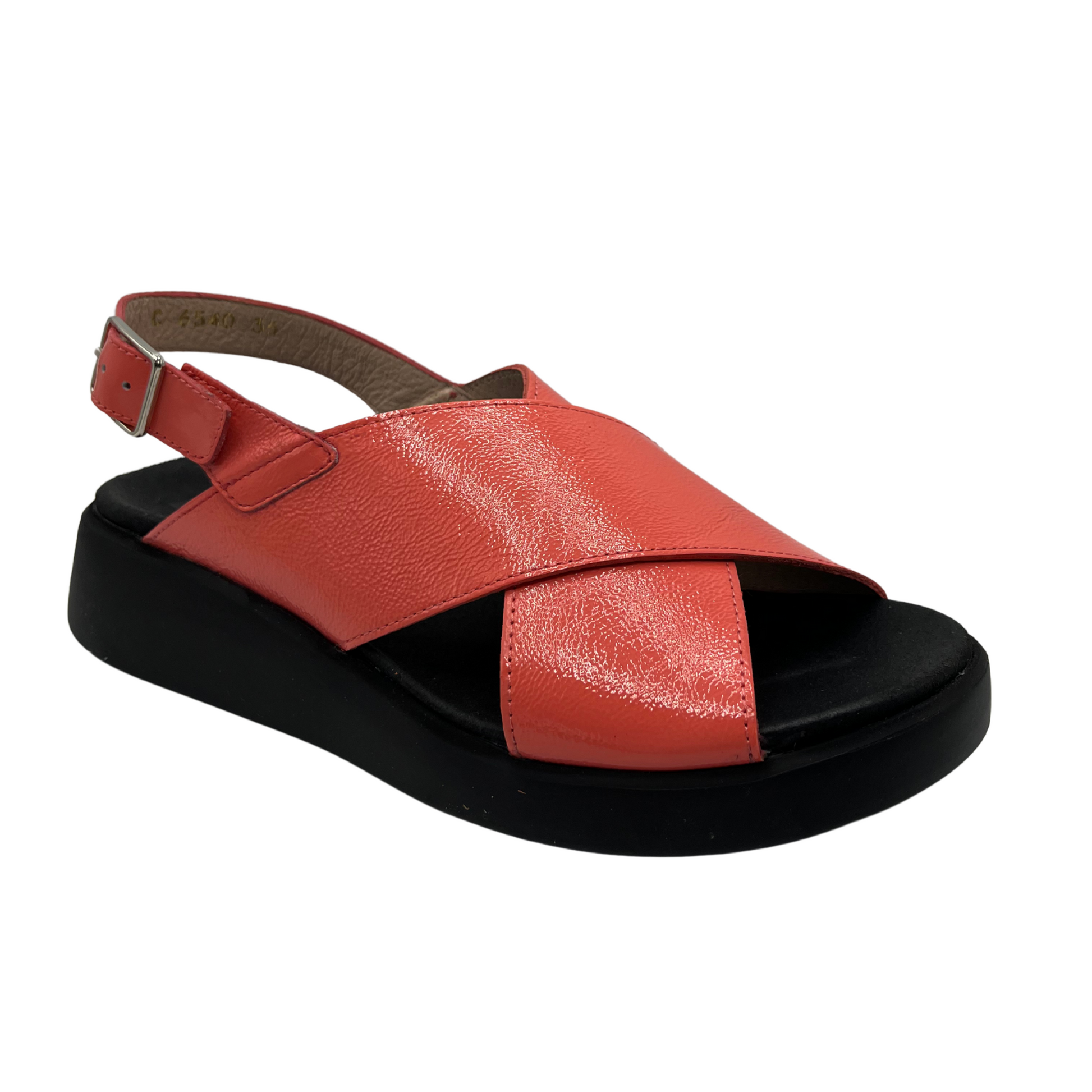 Angled view of coral coloured leather sandal. Black outsole with a contoured footbed and adjustable slingback strap.