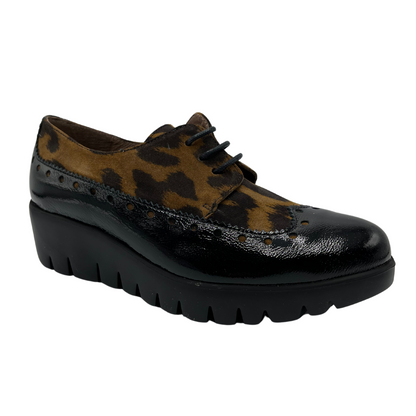 45 degree angled view of leopard print suede and black patent leather shoe with low wedge heel. 