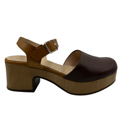 Right facing view of dual toned brown leather clog with a thick wood toned outsole and chunky heel. Silver buckle strap and closed toe.