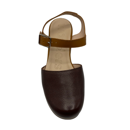 Top view of dual toned brown leather clog with a thick wood toned outsole and chunky heel. Silver buckle strap and closed toe.