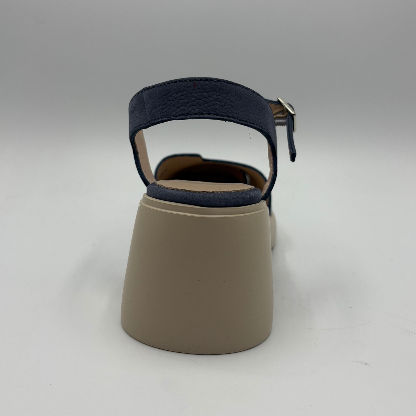 Beige sandal with navy blue strap on a gray background