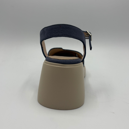 Beige sandal with navy blue strap on a gray background