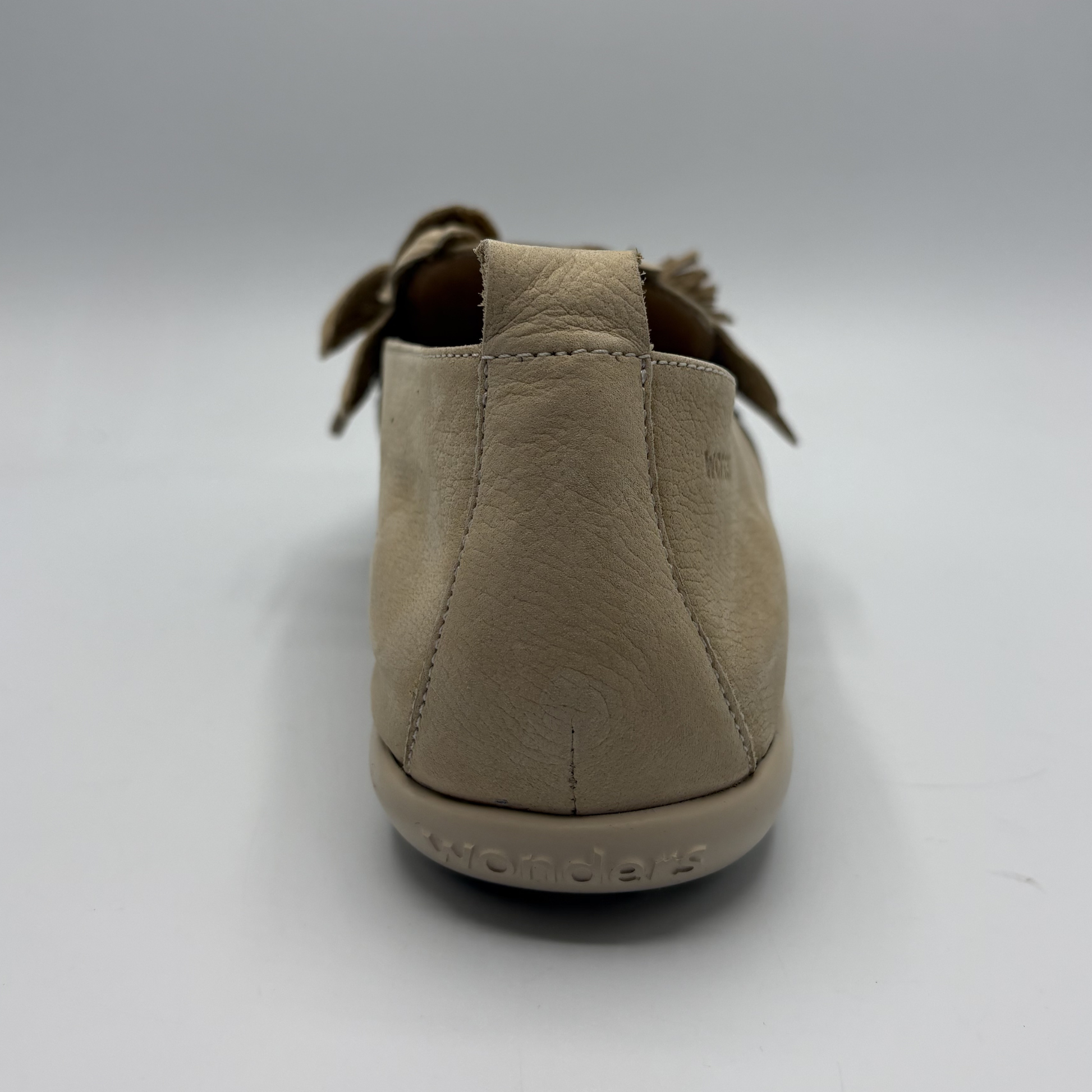 Beige shoe with 'Wonders' branding on a white background