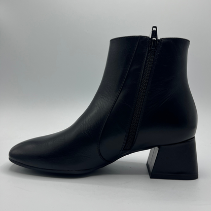 Black ankle boot with a block heel on a light gray background