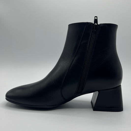 Black ankle boot with a block heel on a light gray background