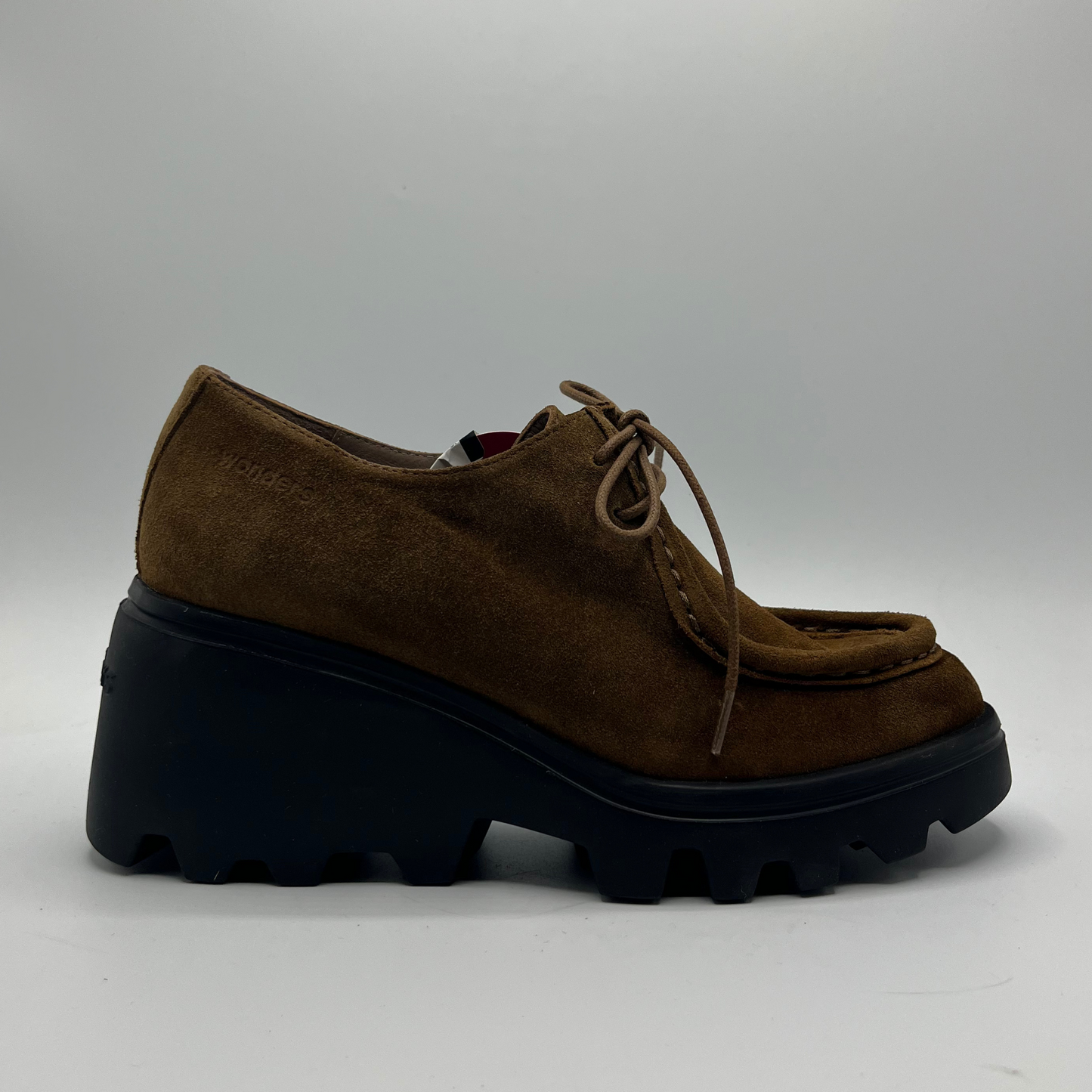 Brown suede shoe with thick black sole on a gray background
