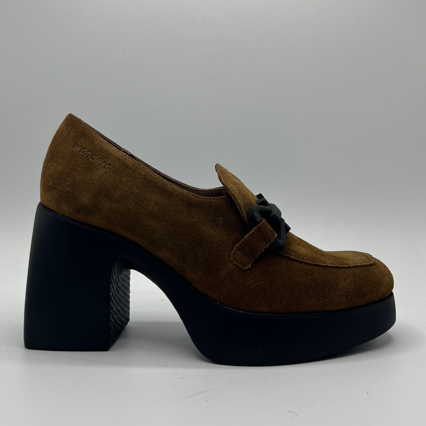 Brown suede shoe with a black platform sole on a gray background