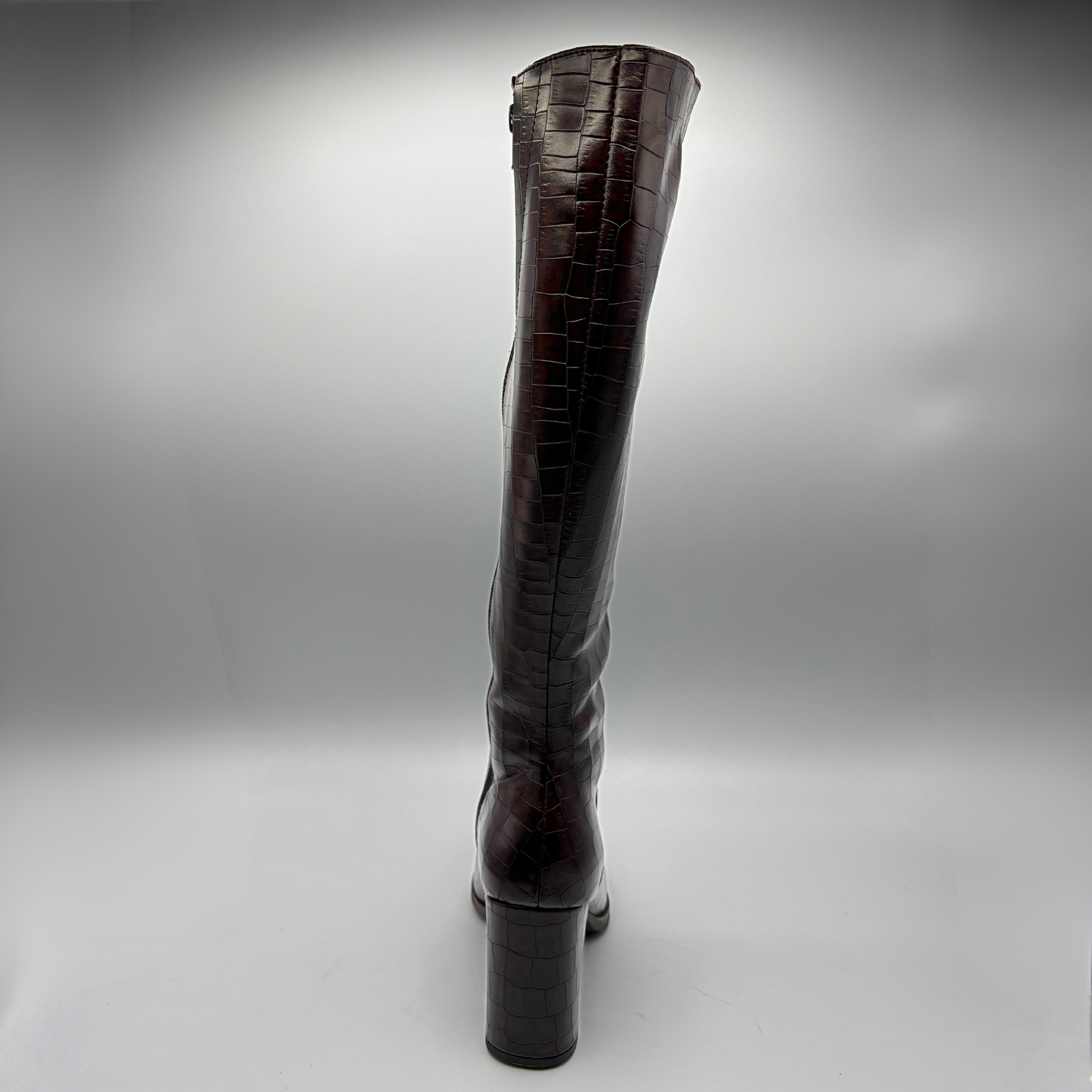 A single dark brown crocodile-embossed leather knee-high boot with a block heel, shown from the back against a gray studio background.