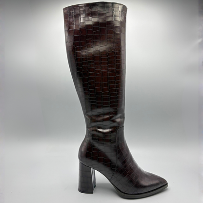A single knee-high boot in glossy dark brown crocodile-embossed leather, shown from the side against a neutral gray studio background.