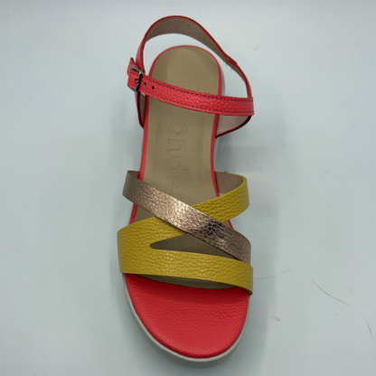 Multicolored sandal with red, yellow, and gold straps on a light gray background