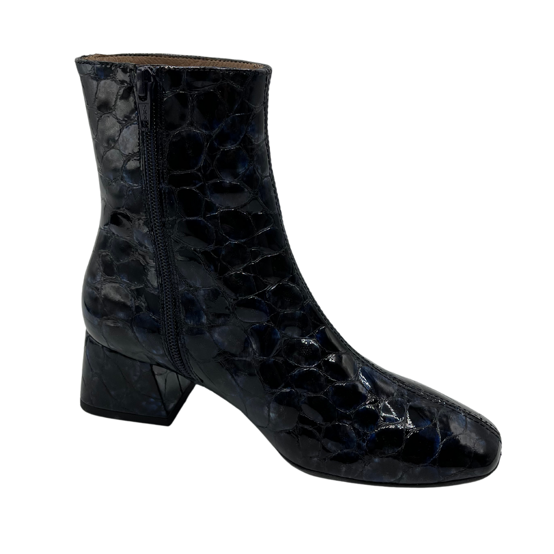 45 degree angled view of deep blue patent textured leather short boot. Short block, side zipper closure and rounded toe