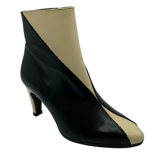 45 degree angled view of black and cream leather bootie with pointed toe and short heel
