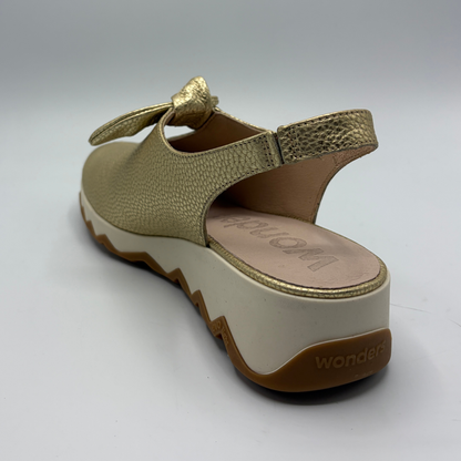 Gold sandal with a white sole on a light gray background