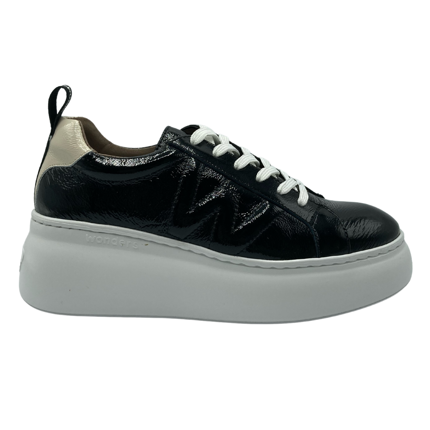 A black patent sneaker with a white platform sole is pictured. There is a cream patent detail on the back of the heel. This sneaker has white lacing.