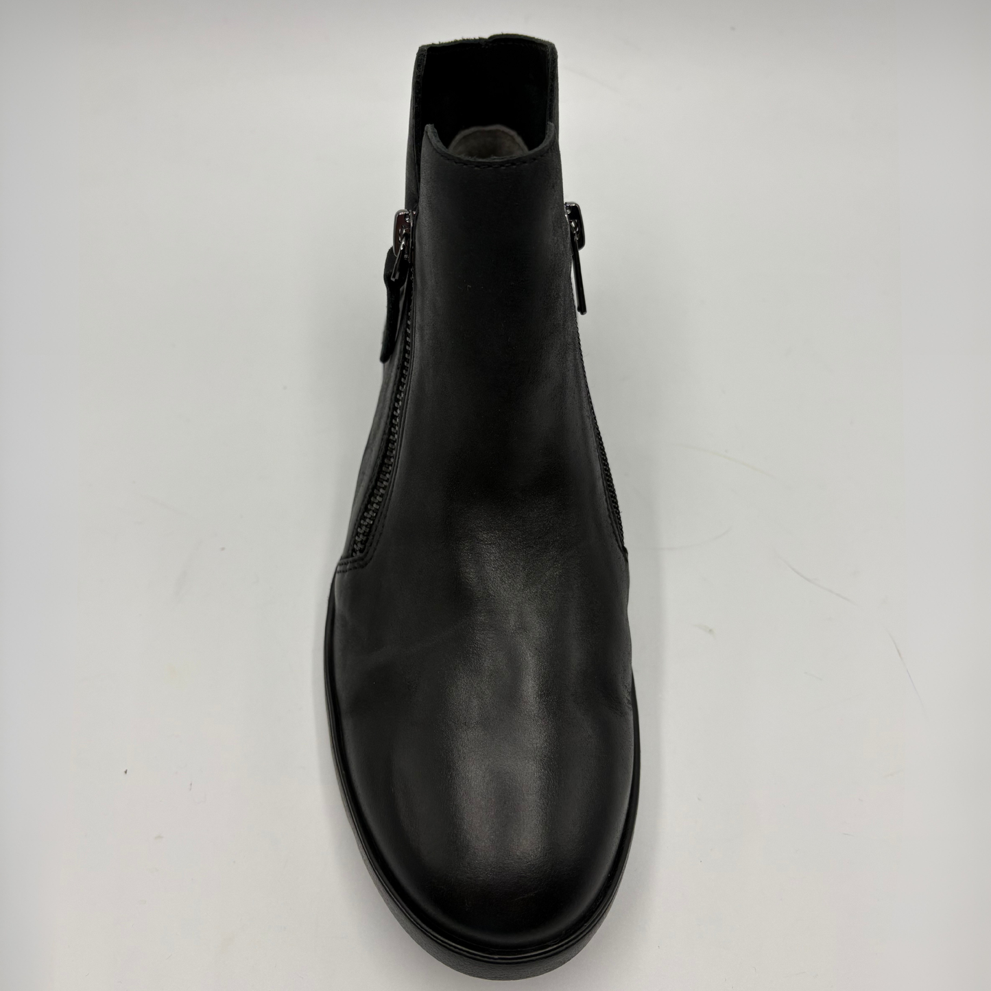 A single black leather ankle boot with a side zipper, shown from a top-down view on a light gray background.