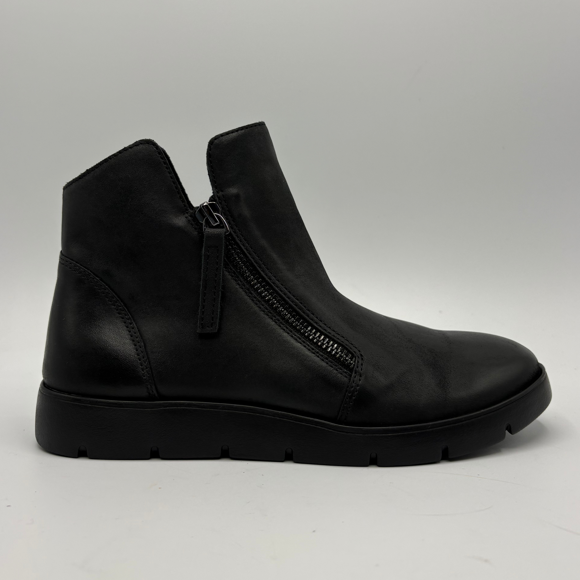 A single black leather ankle boot with a side zipper, shown in profile against a light gray studio background.