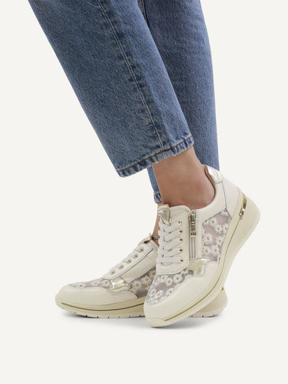 White lace-up sneakers worn with blue jeans on a white background