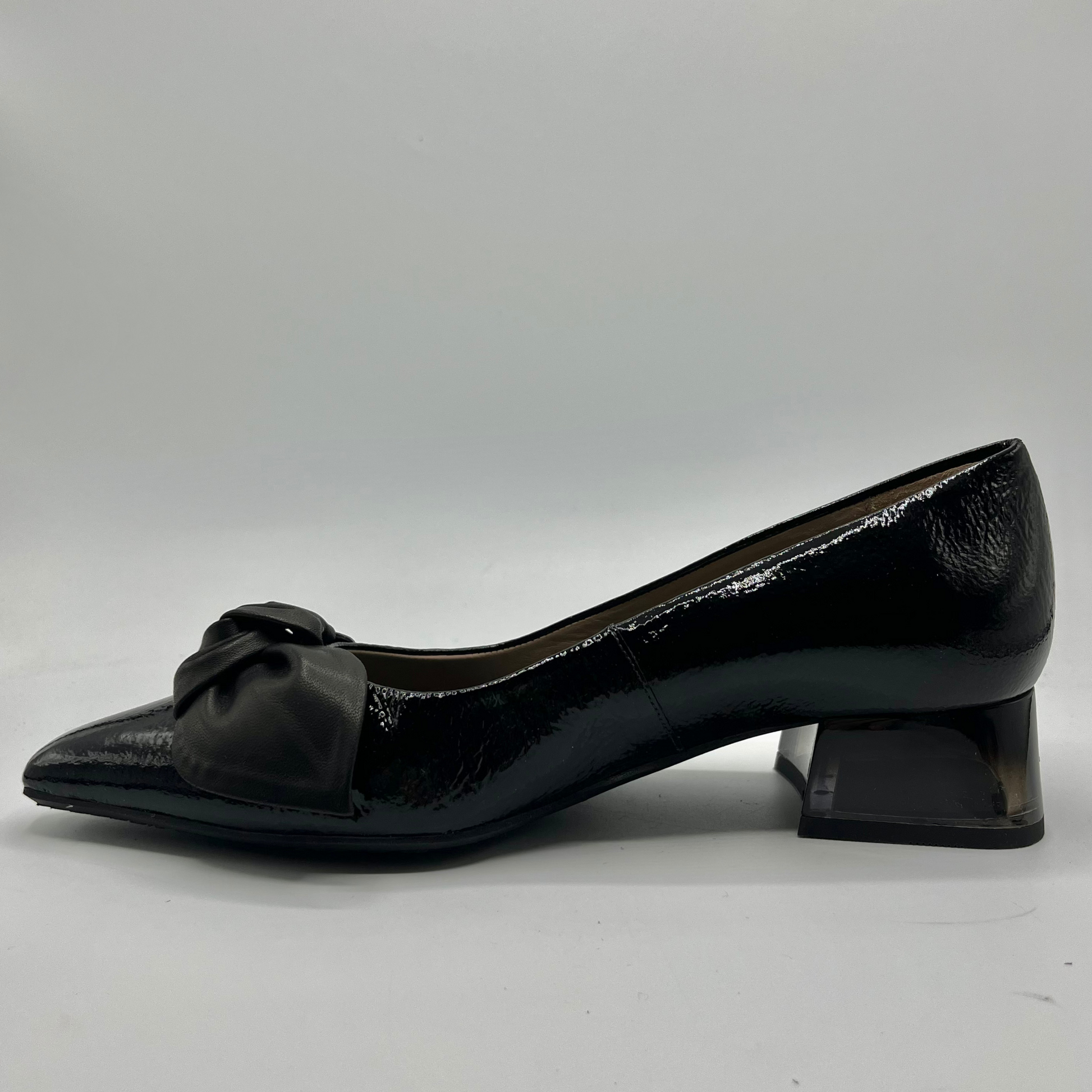 Black patent leather shoe with a bow on a white background