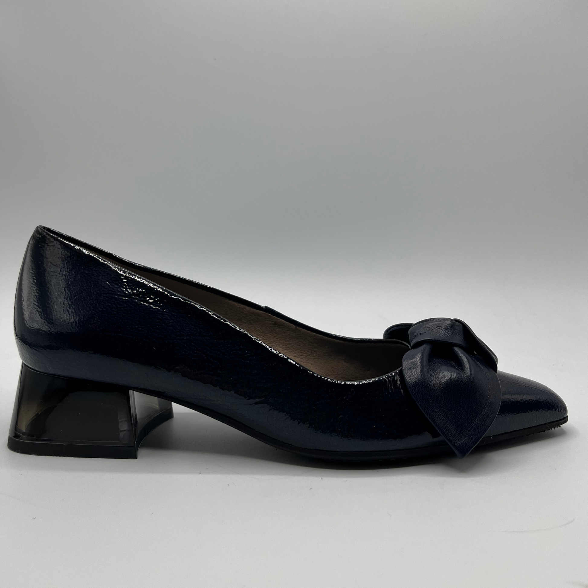 Navy patent leather shoe with a bow on a gray background