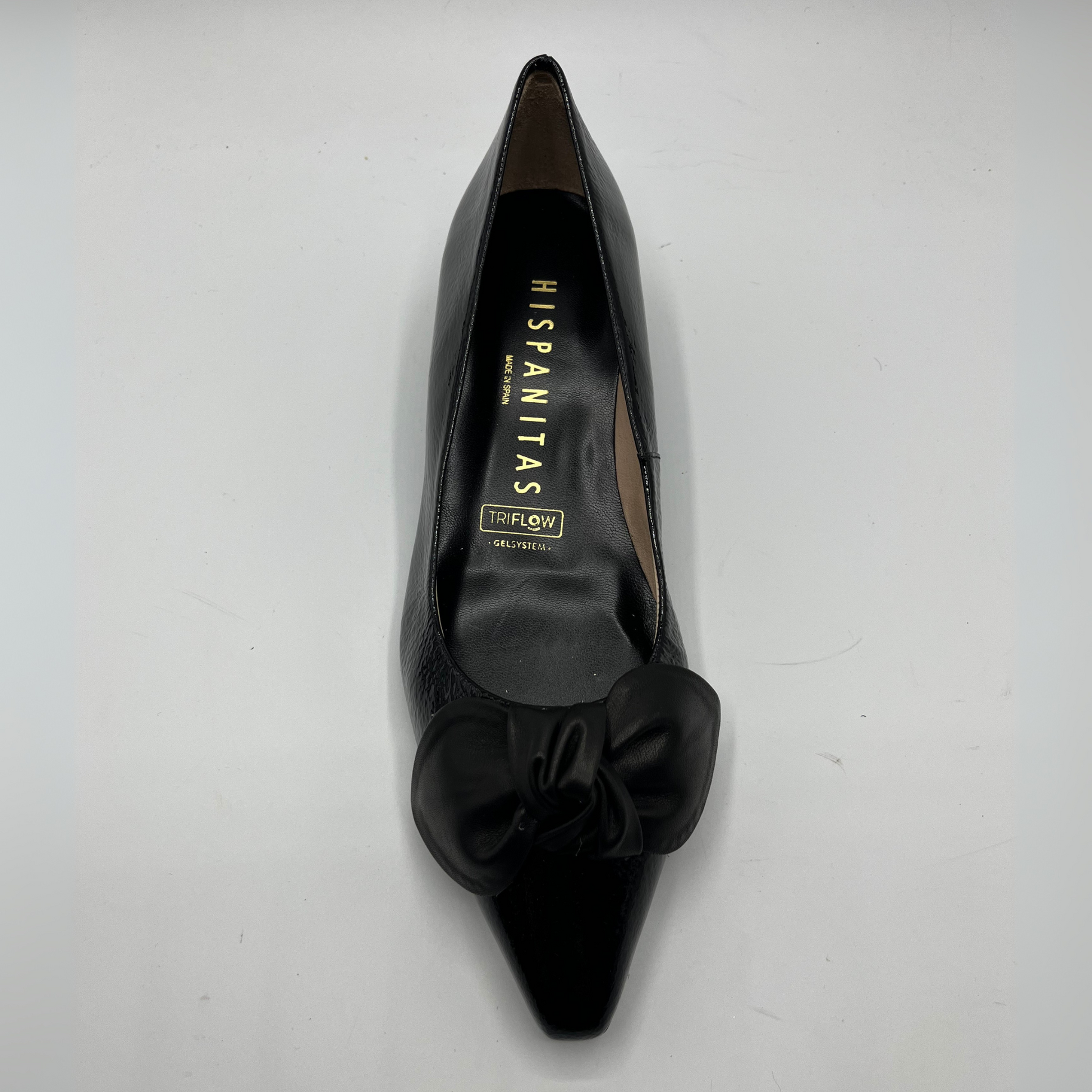 Black pointed-toe shoe with bow detail on a white background