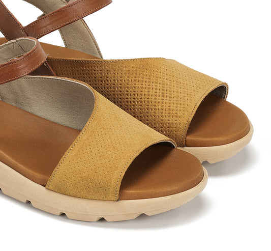 Pair of mustard yellow and brown sandals on a white background