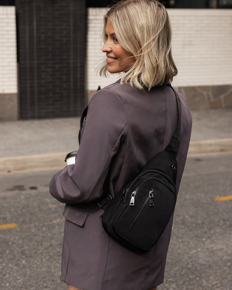 Woman  with a black sling bag on a street.