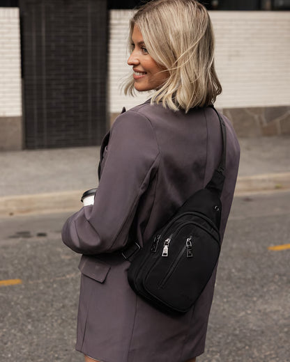 Woman  with a black sling bag on a street.