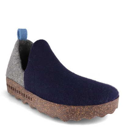 A grey and navy blue wool sneaker with oblong cutouts, blue heel tab, and speckled cork soul is pictured from a 45 degree angle.