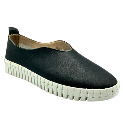 Side angle view of a slip on leather sneaker in black with white rubber sole