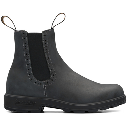 Profile view of the right boot. Rustic black leather boots with brogue accent around elastic sides
