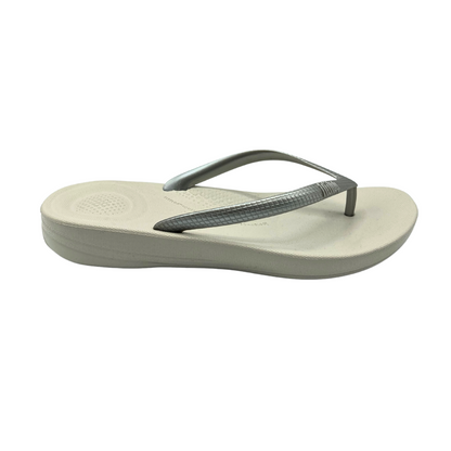 Outside view of a flip flop with a great ergonomic footbed which provides support.  Light taupe colored footbed and silver straps.