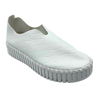 Angled side view of a white slip on sneaker with a white sole.  Upper is a man made material with a woven pattern.  White sole