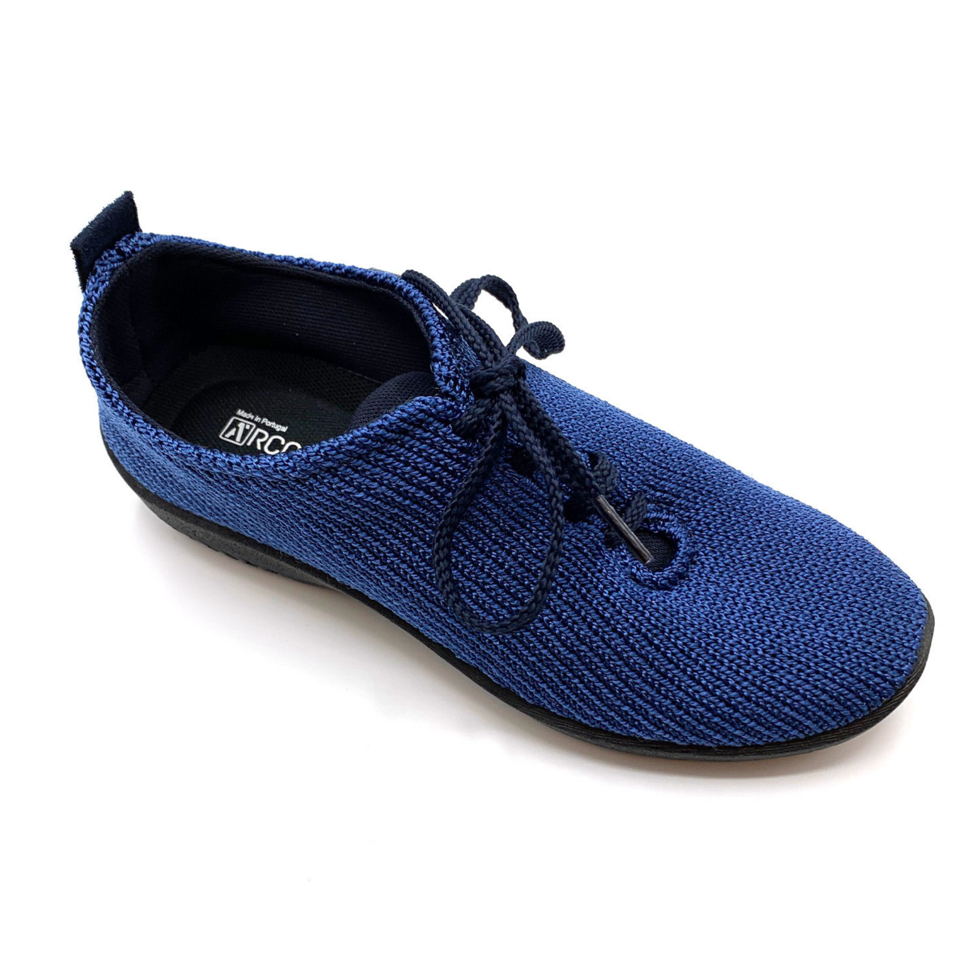 Dark blue sneaker pictured at angle featuring knit upper, black shoe strings, and black lining.