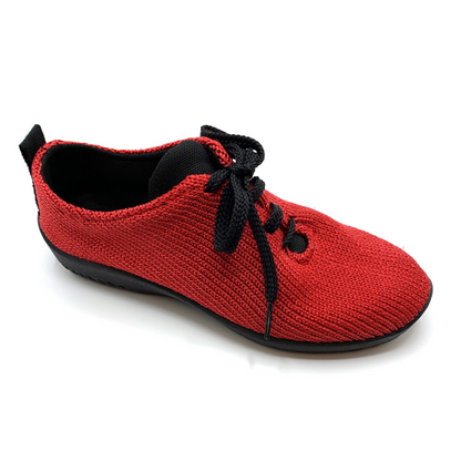Red knit sneaker pictured at slight angle with black sole, lining, and shoestrings.
