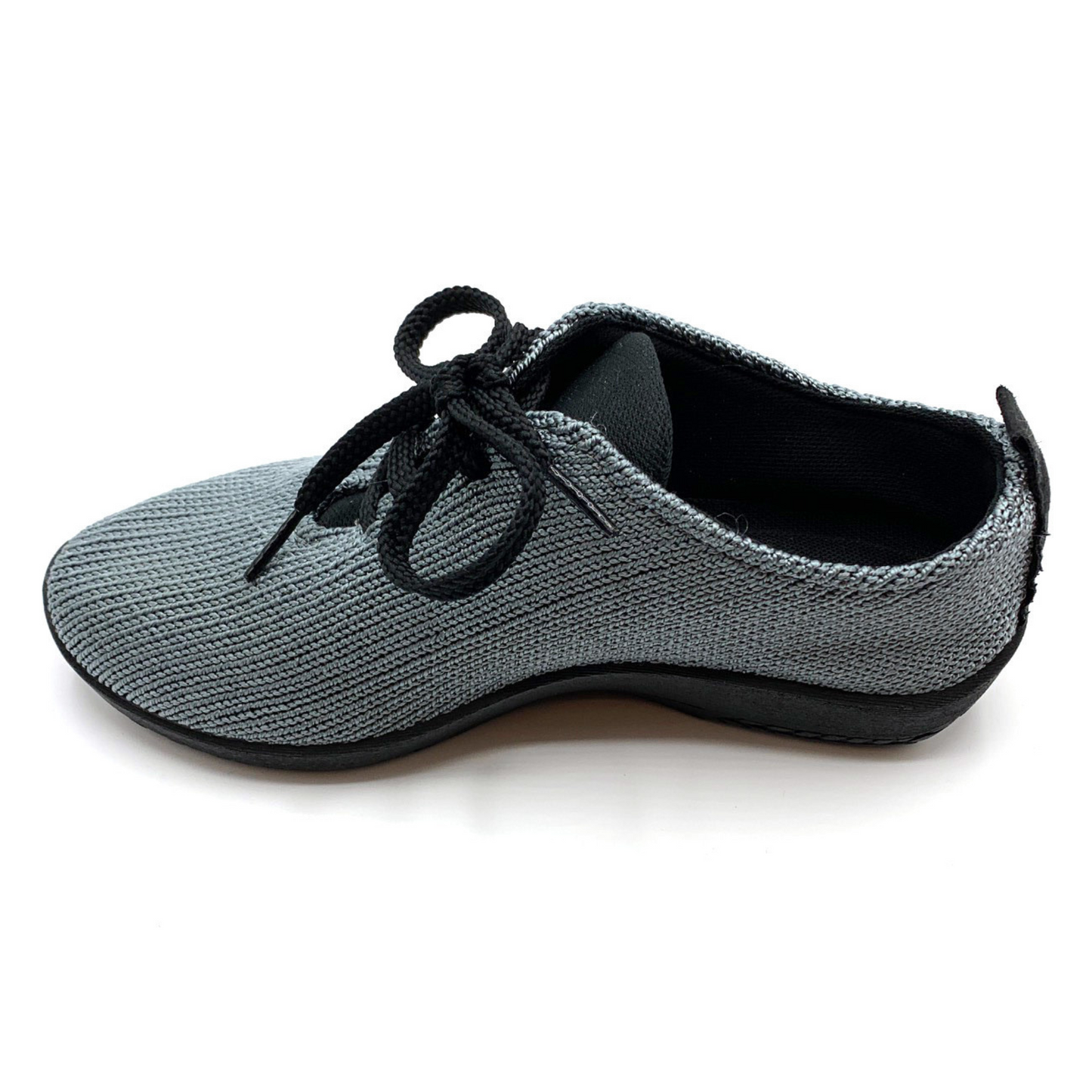 Grey sneaker pictured in profile featuring knit upper, black shoe strings, lining, and sole.