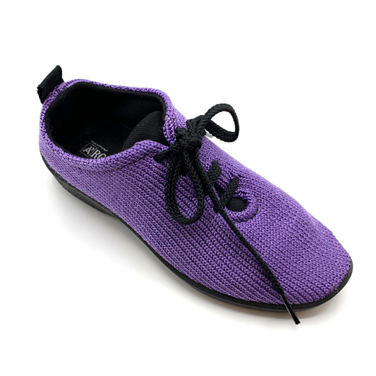 Purple knit sneaker with black lining and lace up strings pictured at an angle.