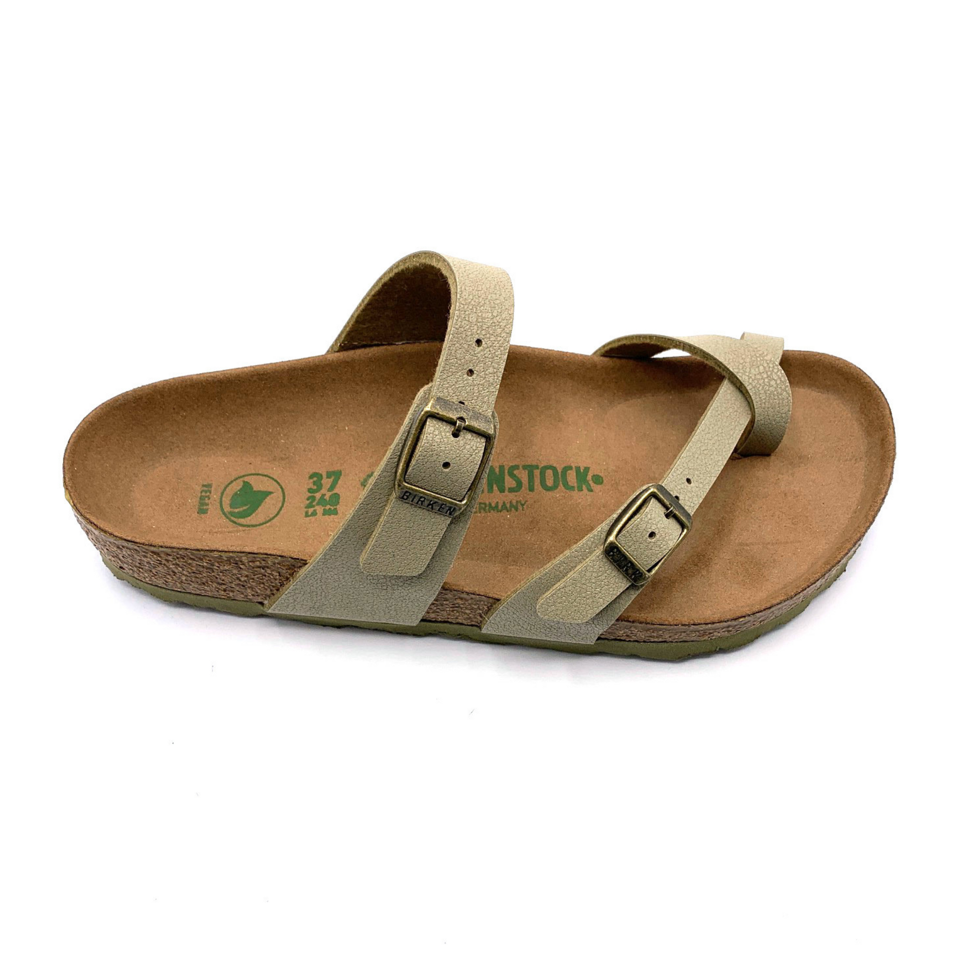 A side angle view of a sandal with a caramel-brown cork sole, two light-khaki straps, and brushed nickel buckles. One of the straps goes over the upper part of the foot, and the other goes between the toes.