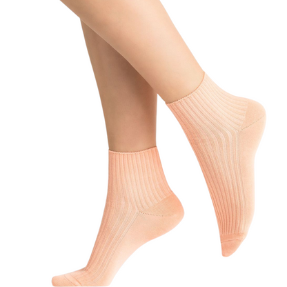 A pair of papaya coloured ankle height socks is pictured with ribbed detailing.