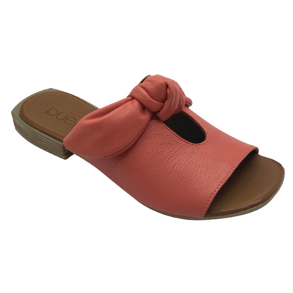 A salmon pink-coral sandal with keyhole cutout, tied detailing, and brown leather sole is pictured in profile.