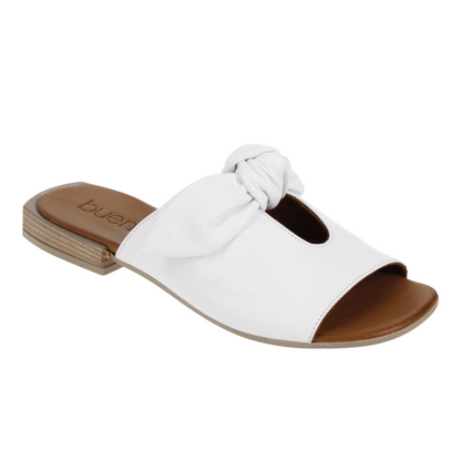 A white leather sandal is pictured from an angle showing a keyhole cutout, and bow tied detailing. The leather sole, block heel and open toe is featured as well.