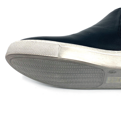 A detailed view shows a leather black shoe with white outsole and a wavy tread.