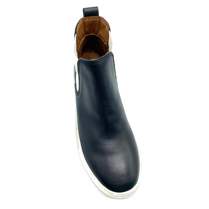A black leather shoe is pictured from the front at an angle with white sole, white side elastic, tan inner leather, and a heel pull tab.