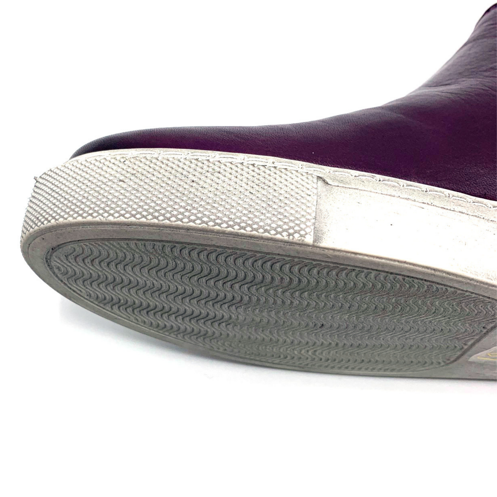 A detailed view shows a leather purple shoe with white outsole and a wavy tread.