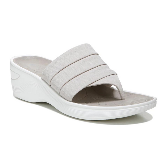 A neutral grey sandal is pictured with pleated mid-foot strap and flip flop strap sits upon a white wedge style platform sole.