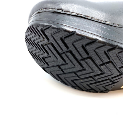 A bottom view of a black clog with a grippy outsole.